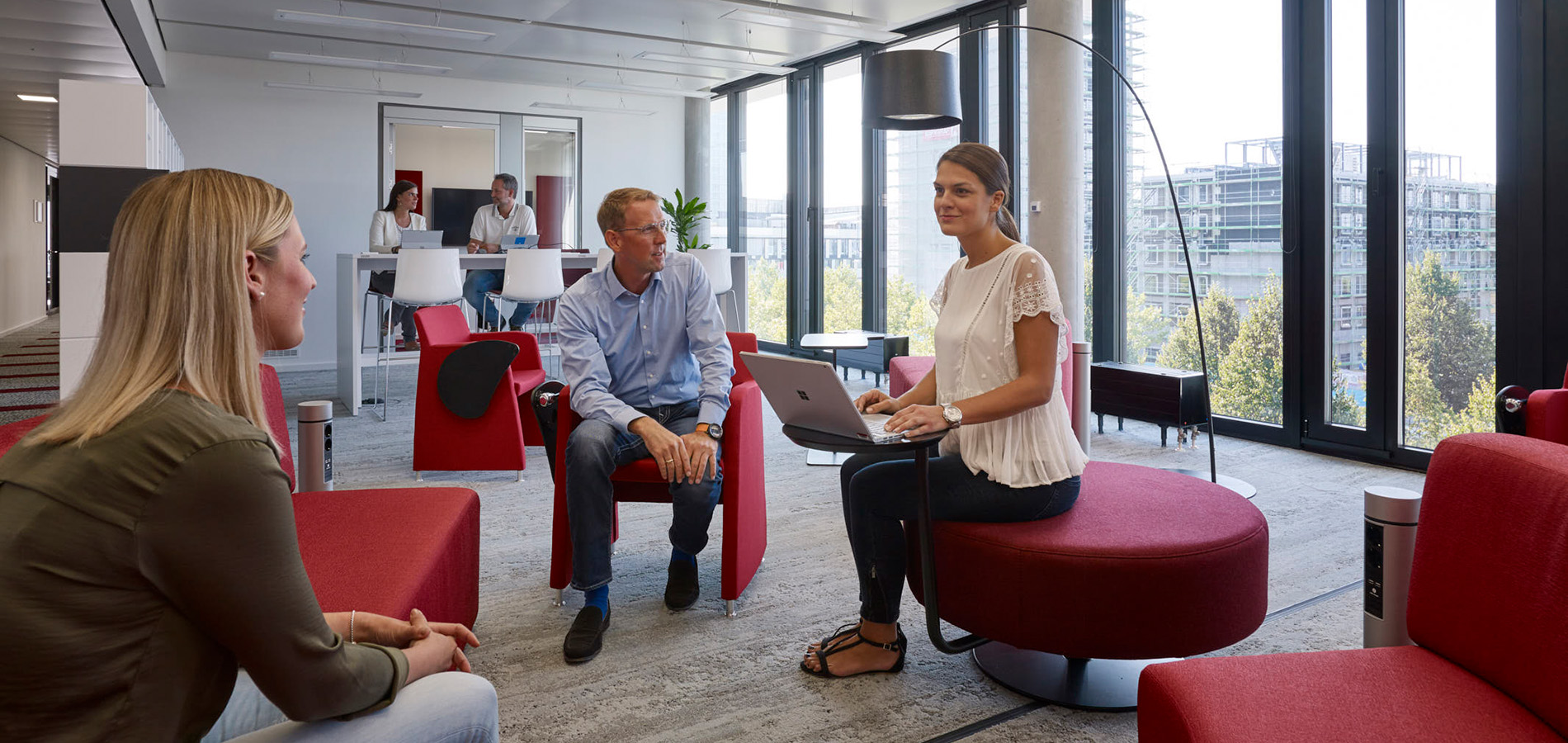 Männer und Frauen sitzen in einer Loungarea in der Unternehmenszentrale zusammen