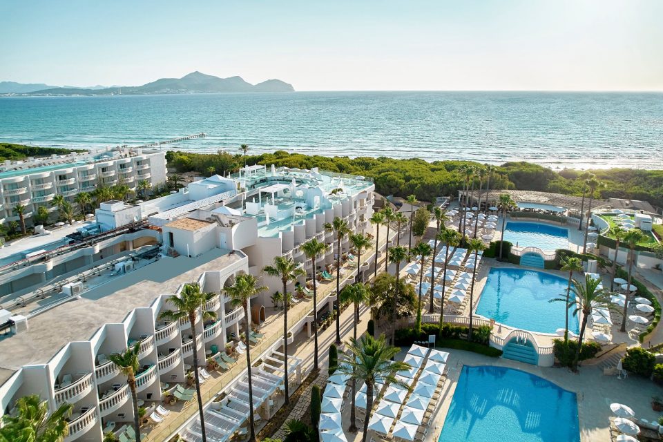 Vista general de un complejo hotelero junto a la costa. Varios edificios con alojamientos en torno a diferentes piscinas.